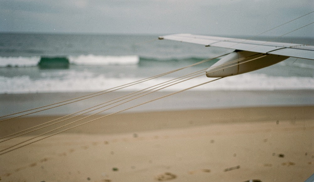Des lignes de traction tendues vers une aile visible de côté sur une plage calme.